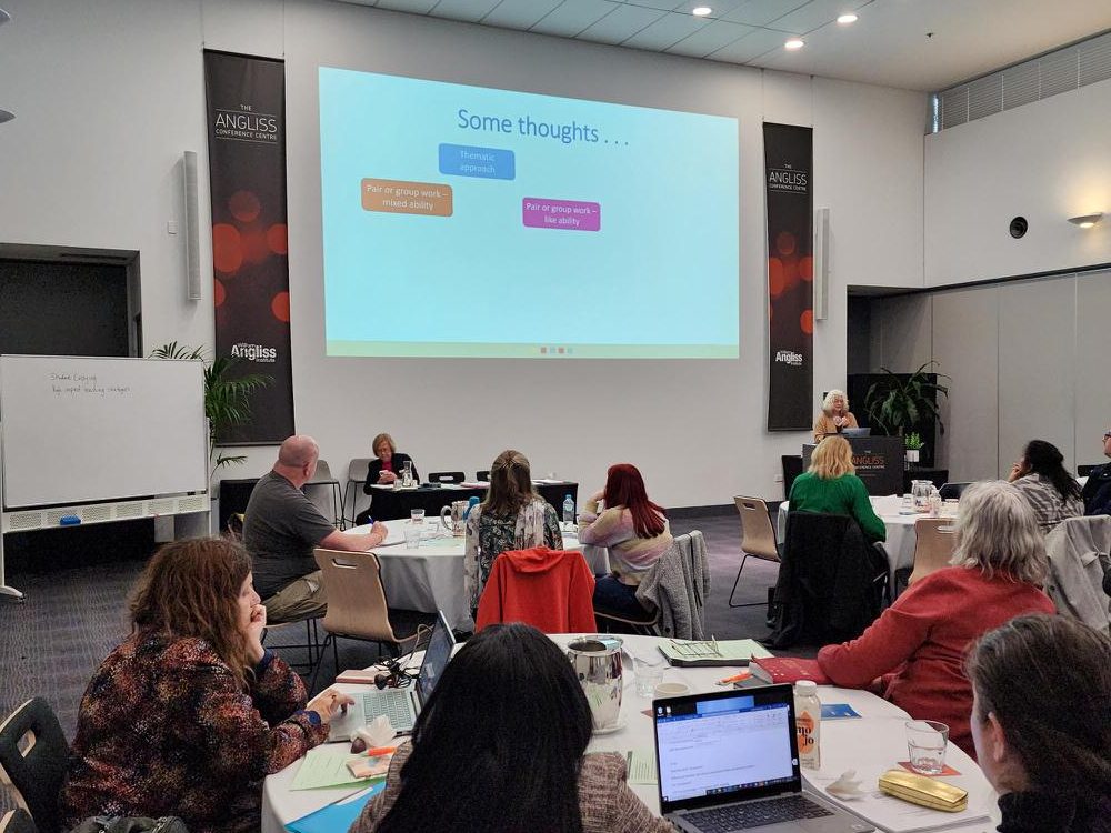 People at tables looking at SEE workshop presentation